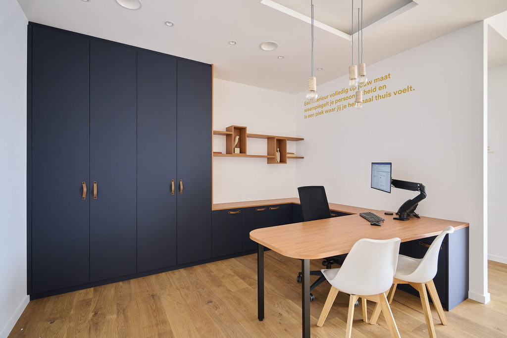Espace de travail avec bureau et placard sur mesure aux portes foncées et accents bois en showroom