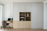 Bureau sur mesure avec rangements fermés et niches ouvertes en bois clair et blanc, décoré avec des objets et plantes.