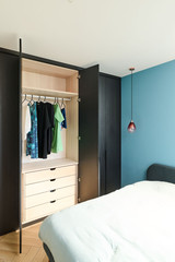 Dressing sur mesure avec tringle à vêtements et tiroirs intégrés en décor bois dans une chambre