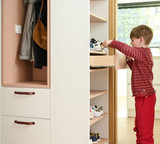 Kind dat schoenen uit een Camber vestiaire op maat neemt, met open schoenenrek, geïntegreerde lades en een toegankelijke indeling op kinderhoogte