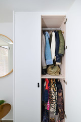 Armoire d'entrée fermée sur mesure avec étagères et porte pour manteaux, disposée dans un hall clair et moderne.