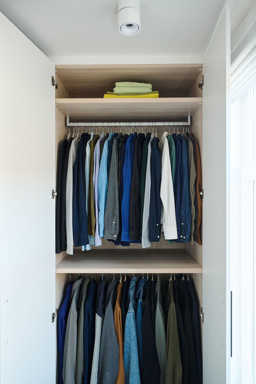 Open maatkast met dubbele hangrail voor hemden en vesten en bovenaan legplank met opgevouwen kleding