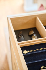 Gros plan d'un tiroir en bois avec compartiments pour lunettes et bijoux, doté d'un fond en velours noir et d'une médaille en or.