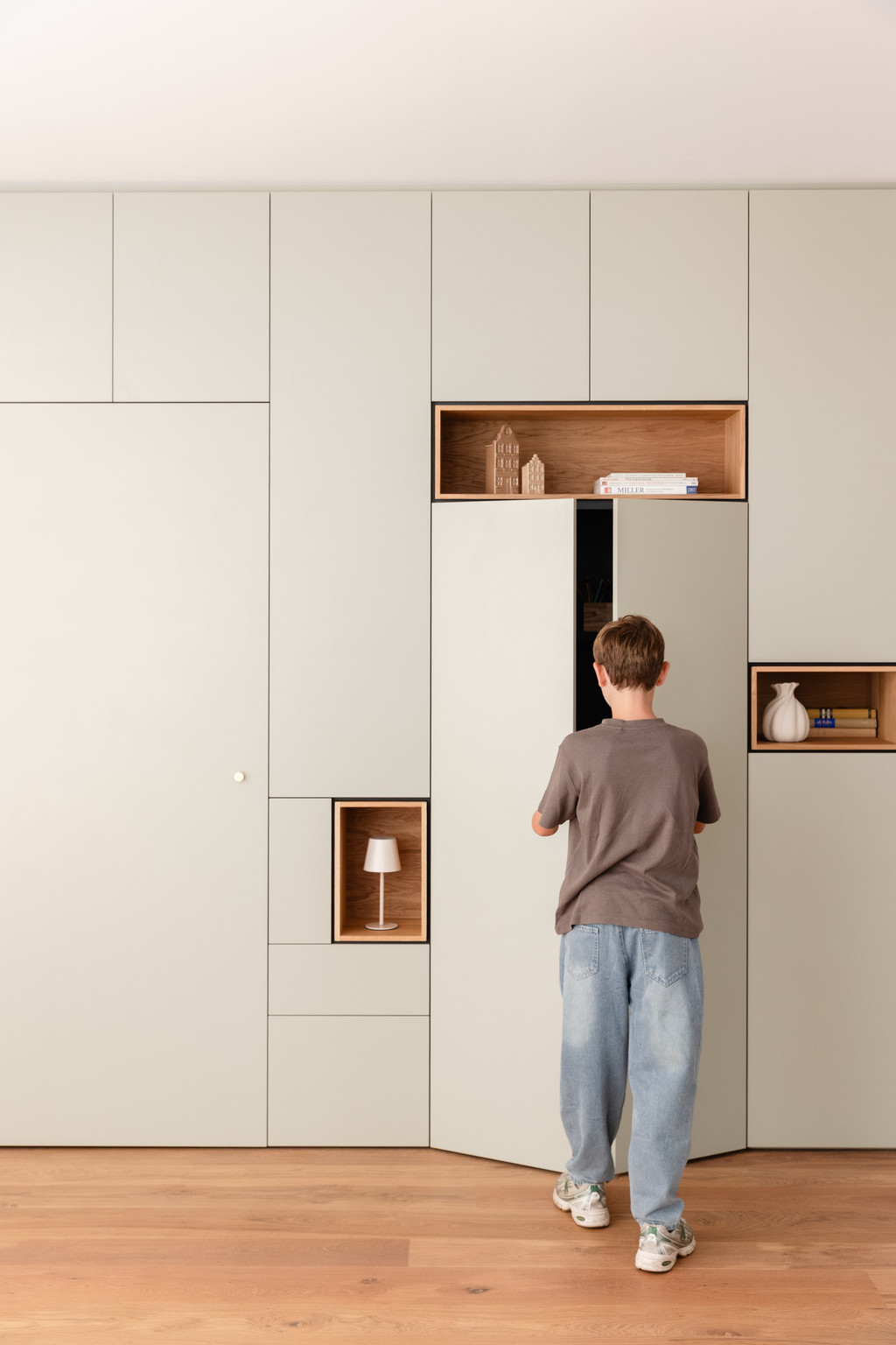 Bibliothèque sur mesure sans poignées avec bureau escamotable dissimulé, alliant design épuré et espace de travail discret intégré dans le séjour