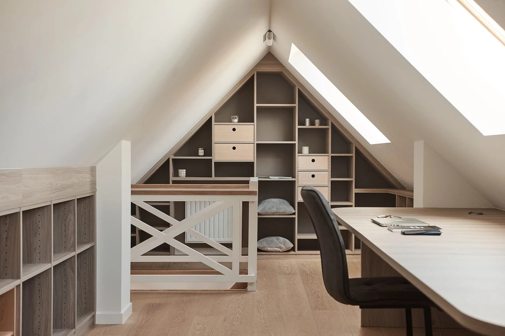 Aménagement sous toit avec étagères ouvertes et tiroirs, espace de rangement sous pente avec bureau et lumière naturelle.
