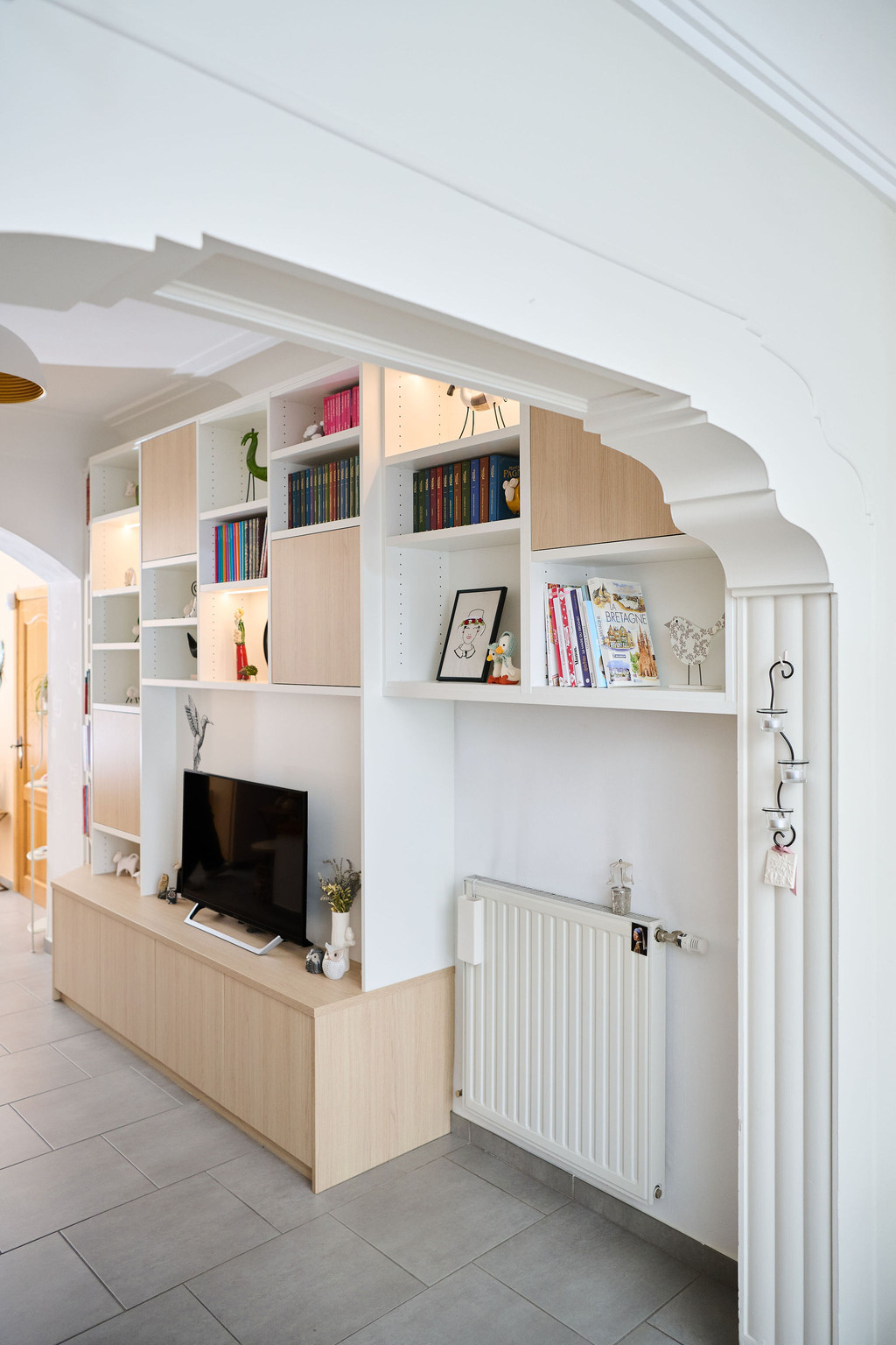 Meuble TV sur mesure avec niches ouvertes et fermées dans un salon avec vue sur le couloir