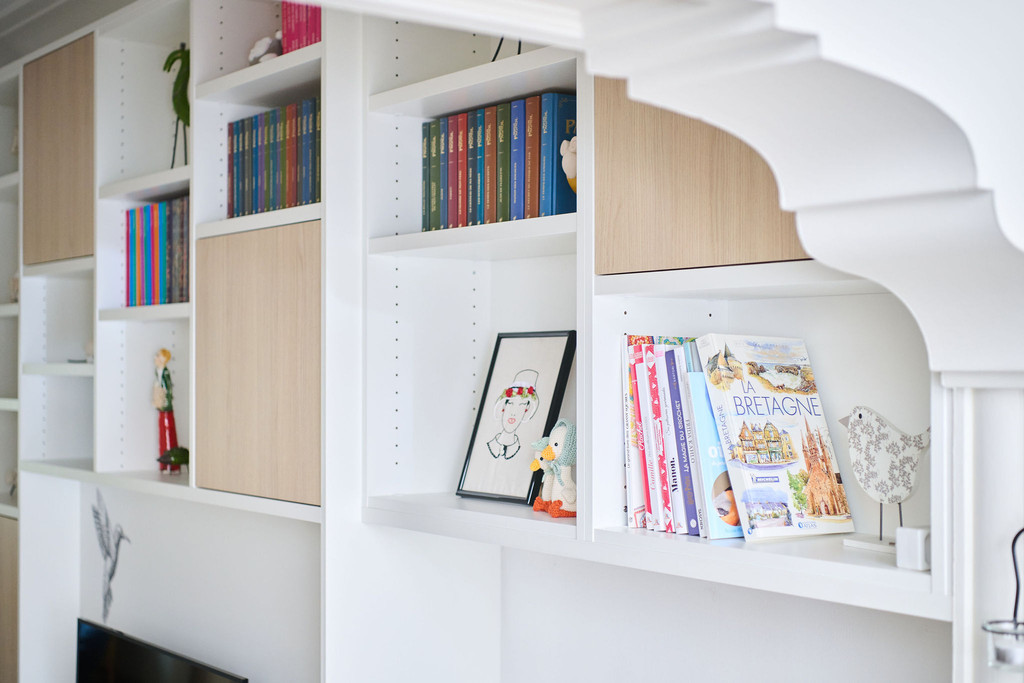 Détail de niches ouvertes et fermées d’un meuble TV blanc sur mesure avec livres et décorations
