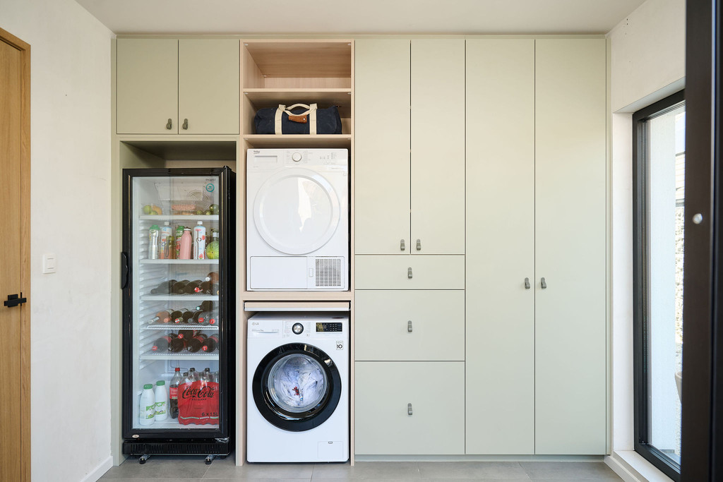 Camber wasruimte op maat met geïntegreerde wasmachine en droogkast in kolom, gesloten maatkasten en extra opbergruimte in een strak en functioneel geheel
