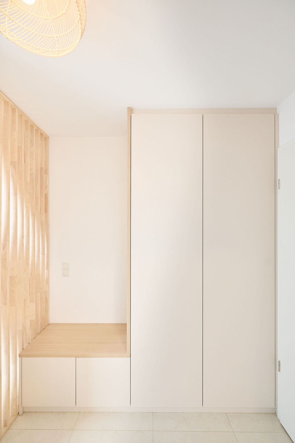 Op maat gemaakte vestiairekast in neutrale tinten met een geïntegreerde zitbank en gesloten opbergruimte voor een strakke inkomhal.