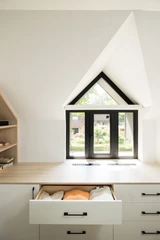 Dressing sur mesure sous pente avec fenêtre, étagère ouverte et plan de travail, apportant lumière et praticité.