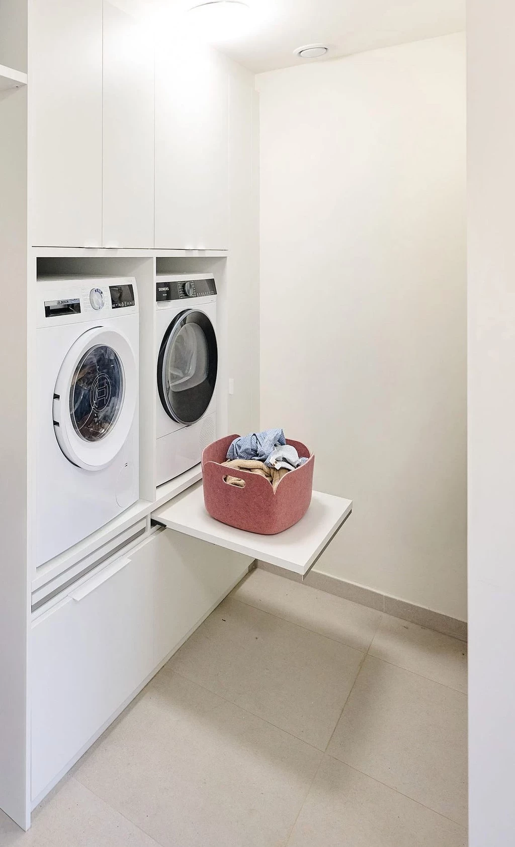 Buanderie sur mesure avec machine à laver et sèche-linge encastrés, tablette dépliable et meubles de rangement intégrés.