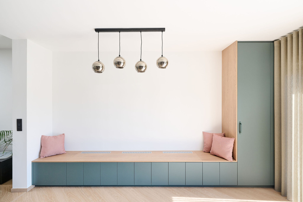 Banquette murale verte avec coussins roses et suspension design au plafond