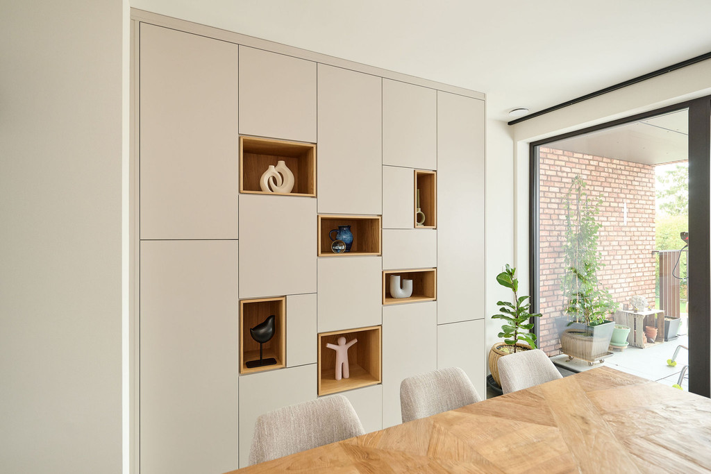 Placard sur mesure avec niches ouvertes en finition bois et accents chaleureux, intégré dans une salle à manger lumineuse pour allier rangement et décoration, réalisé par Camber