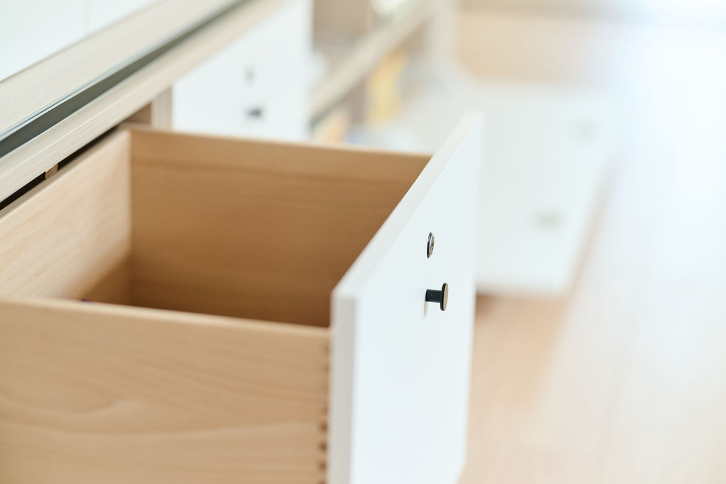 Tiroir en bois ouvert dans un meuble blanc sur mesure avec bouton noir