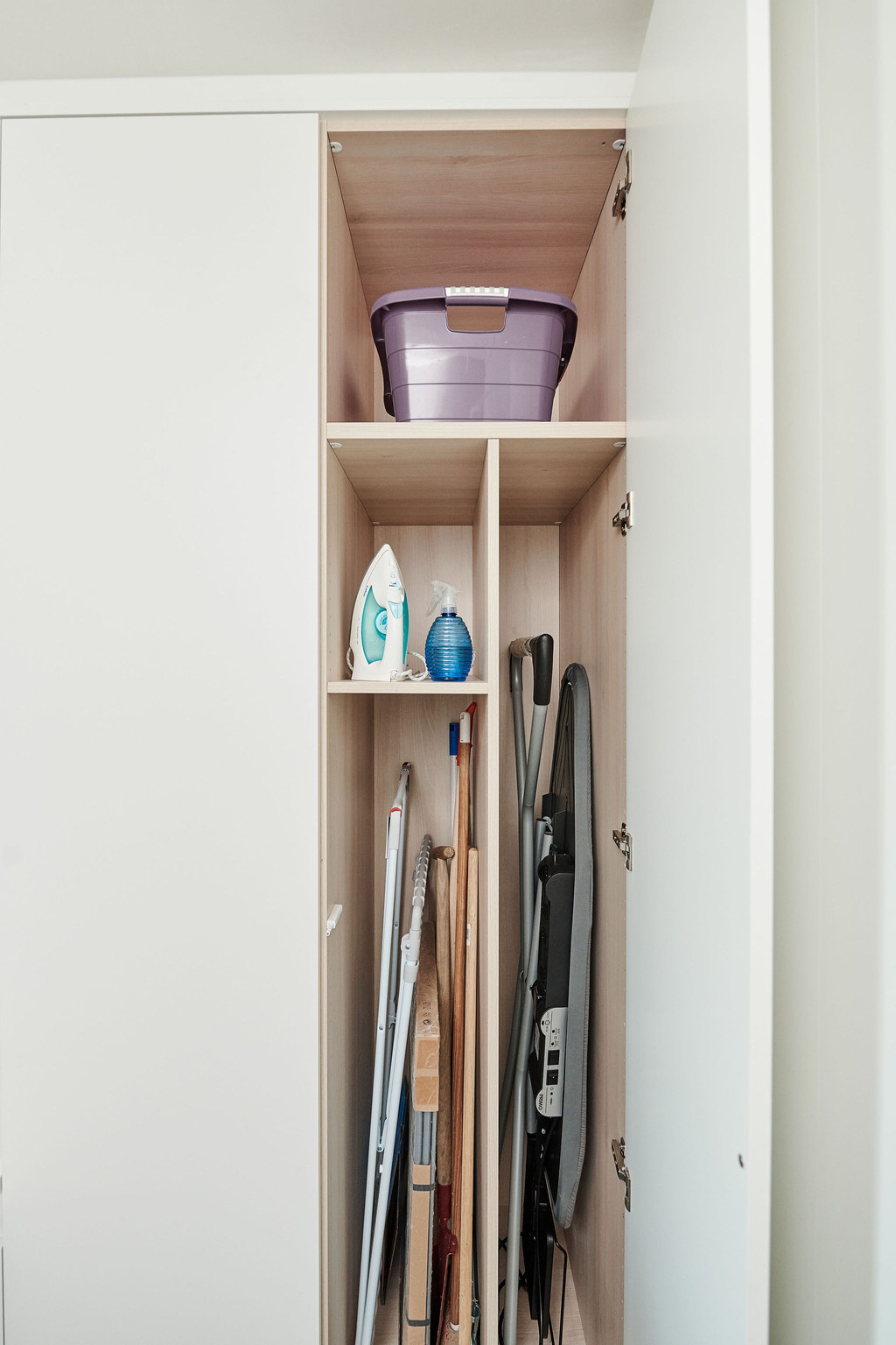 Meuble de rangement sur mesure dans une buanderie avec étagères pour produits ménagers et accessoires de nettoyage.
