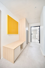 vestiaire avec structure blanche et chêne dans le couloir avec portes