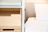 Opklapbed met geïntegreerde lades en bed in kamer met witte lakafwerking.