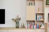 Meuble TV sur mesure avec niches ouvertes et fermées, décoré avec des livres, une plante et des accessoires, offrant un design moderne et fonctionnel.