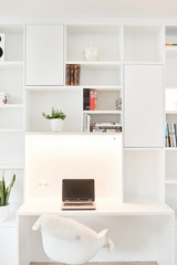 Bureau blanc avec étagères et rangements, plateau éclairé et éléments décoratifs.