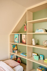 Bibliothèque sur mesure en bois clair avec fond vert et livres pour enfants exposés