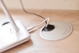 Prise de câble intégrée dans un bureau sur mesure avec un câble de recharge branché.