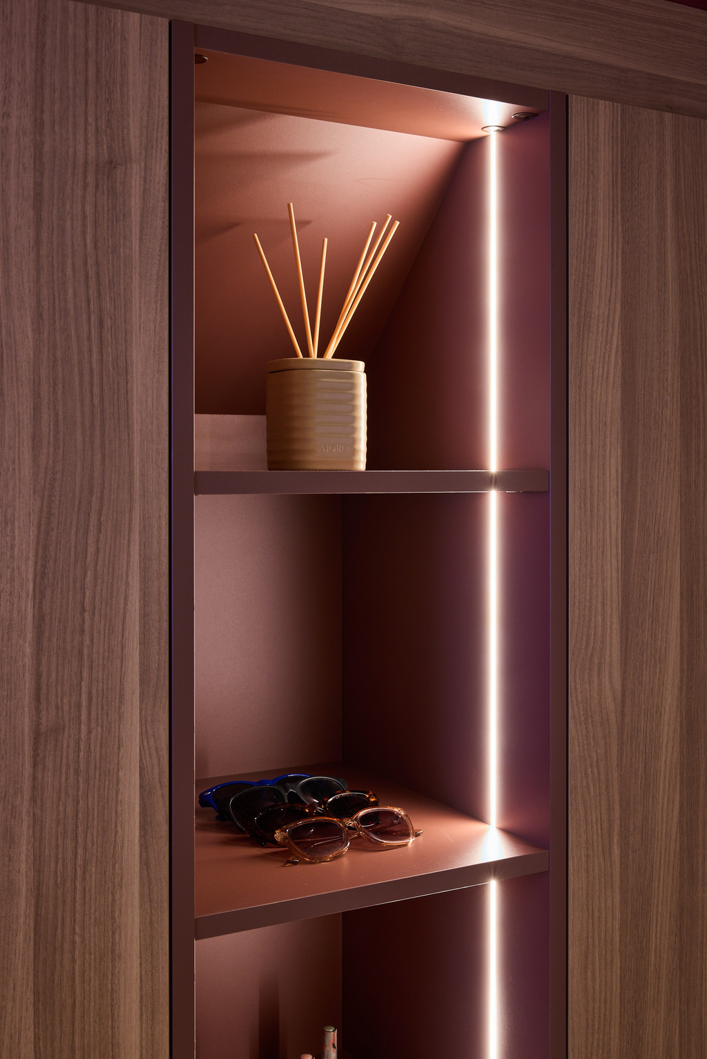 Niche ouverte dans un placard sur mesure avec éléments décoratifs et éclairage LED vertical dans des tons chaleureux