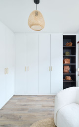 Dressing fermé sur mesure avec portes blanches et poignées dorées, accompagné d’étagères noires ouvertes pour le rangement des sacs à main.