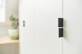 Detail van een witte maatkast onder een schuine wand met moderne zwarte handgrepen, minimalistisch ontwerp met subtiele schaduwen.
