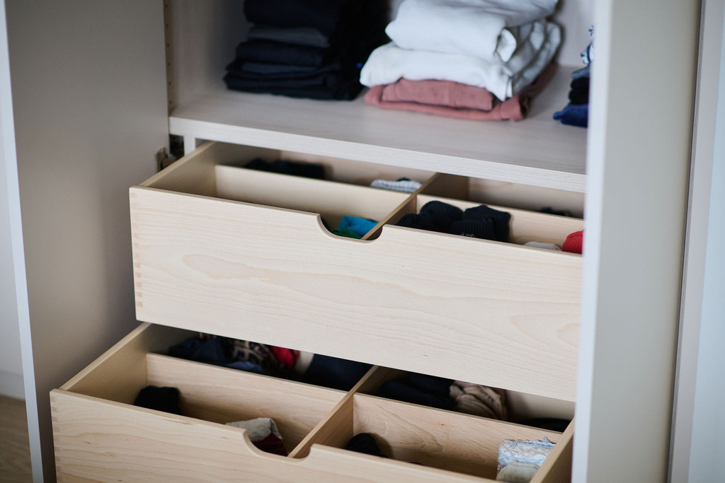 Tiroirs ouverts avec compartiments dans une armoire de chambre sur mesure contenant des vêtements pliés