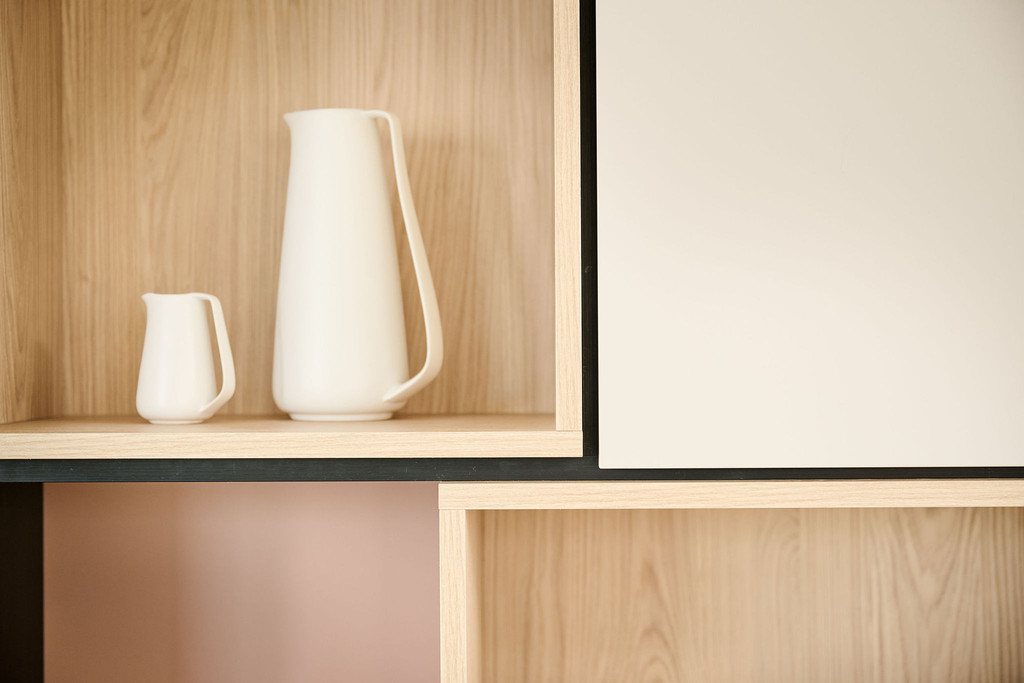 Zoom sur une niche ouverte en bois avec deux pichets blancs décoratifs dans un meuble mural sur mesure