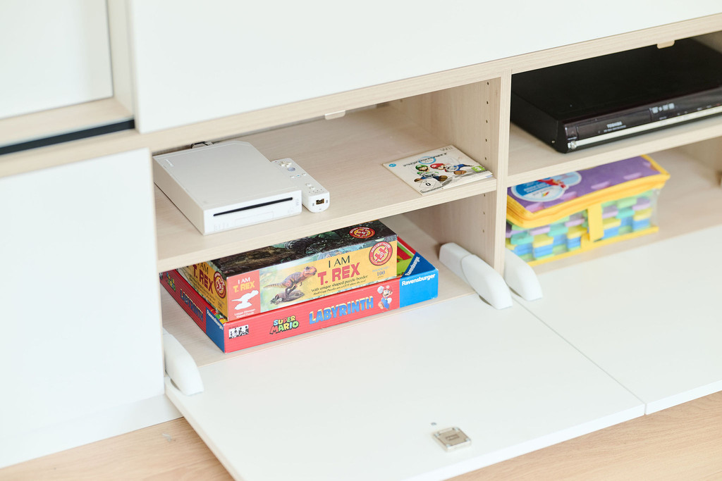 Tiroir ouvert avec jeux de société et console dans un meuble blanc sur mesure