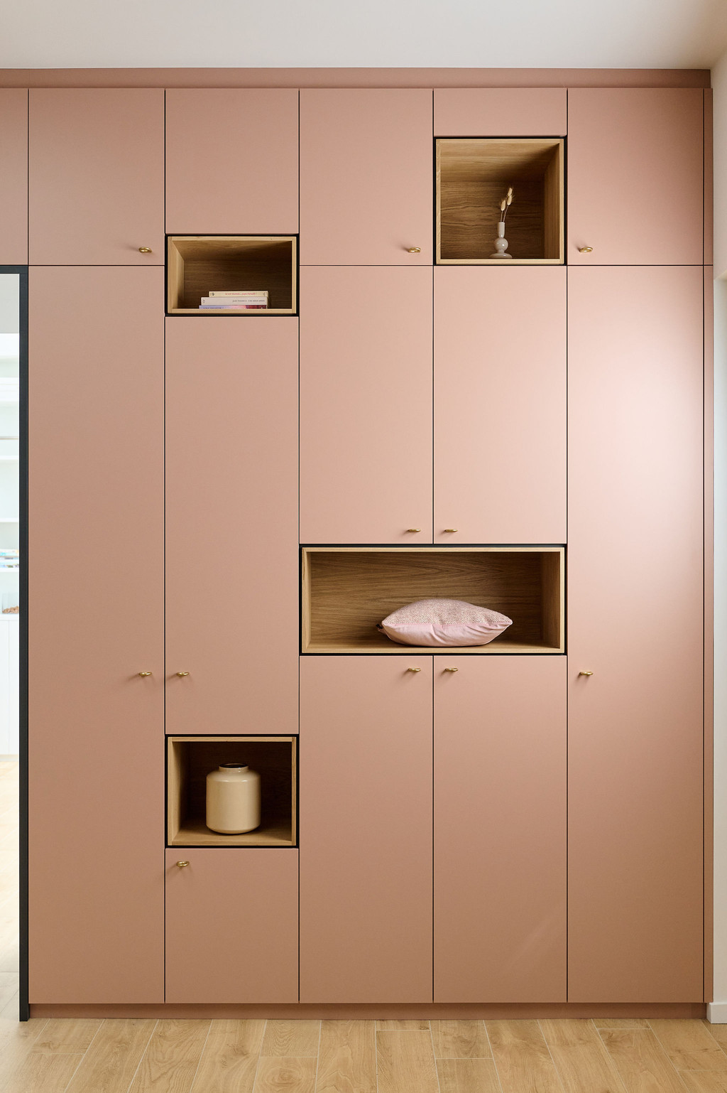 roze boekenkast op maat met open compartimenten en draaideuren