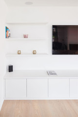 Meuble TV bas blanc sur mesure avec étagères murales assorties et écran plat fixé au mur.
