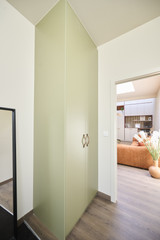 Armoire d’angle sur mesure vert doux dans un hall d’entrée avec vue sur le salon