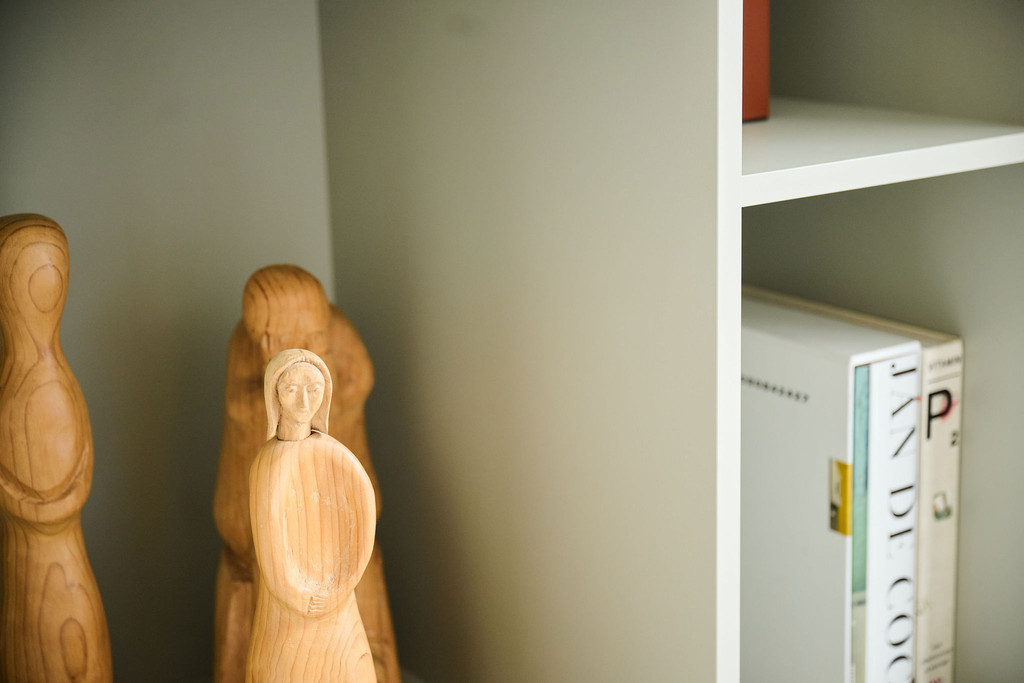 Gros plan sur des sculptures en bois dans une niche ouverte d’un meuble blanc aux tons doux