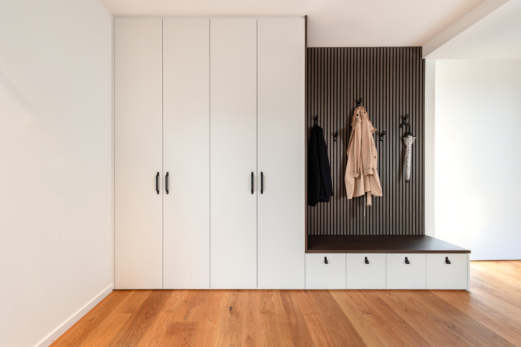 Strakke inkomhal met ingebouwde vestiairekast, houten zitbank met opberglades en wandhaken voor jassen en accessoires