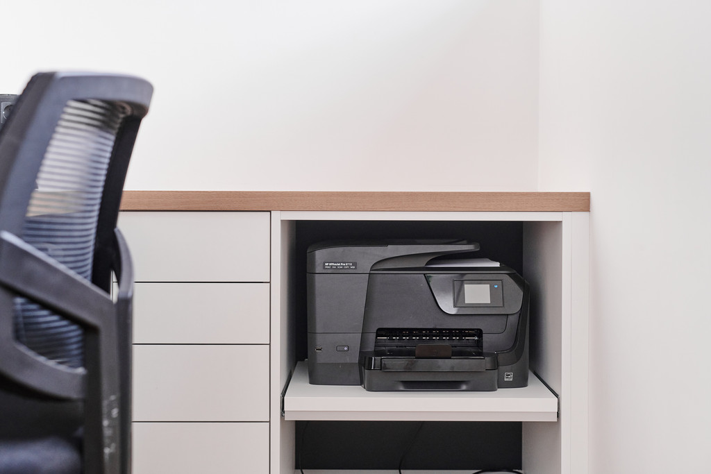 Détail d’un meuble de bureau sur mesure avec imprimante escamotable et rangement optimisé.