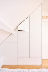 Placard sur mesure encastré sous pente avec portes minimalistes dans une chambre d’enfant