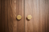 Gros plan sur des portes de placard en bois avec des poignées rondes dorées, apportant une touche élégante et chaleureuse à l’espace.