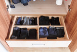Tiroir de rangement sous pente avec des vêtements pliés, organisés en compartiments pour un rangement optimal.