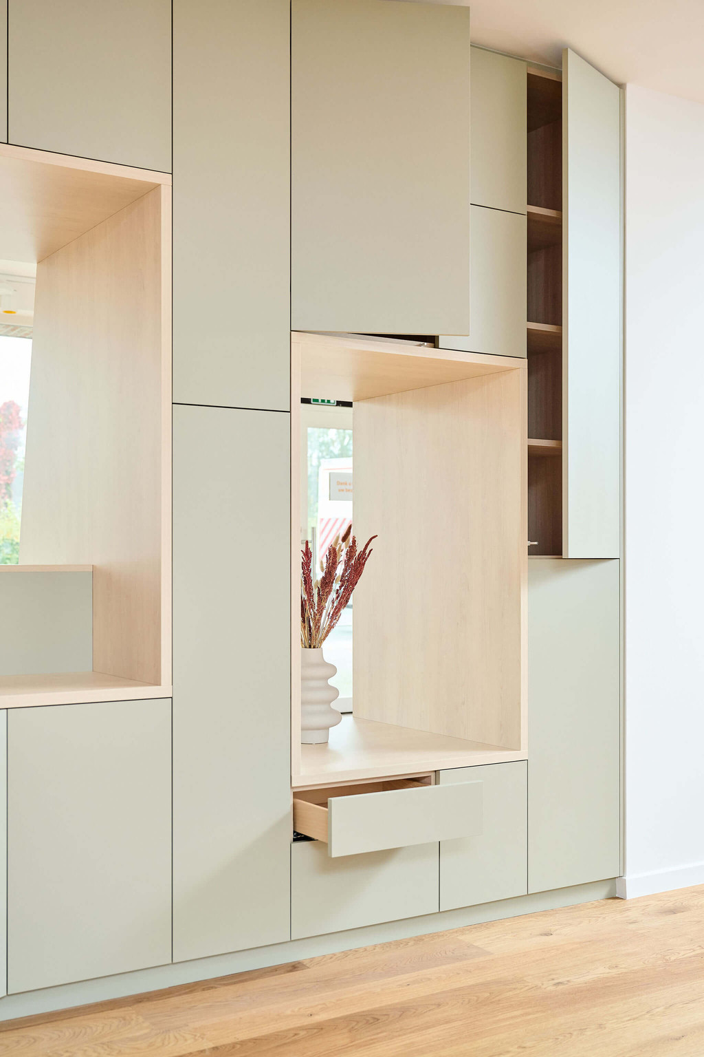 Meuble salon en vert sauge sur mesure avec des tiroirs et portes fermés