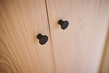 Close-up van twee ronde zwarte knoppen op houten kastdeuren van op maat gemaakte vestiairekast