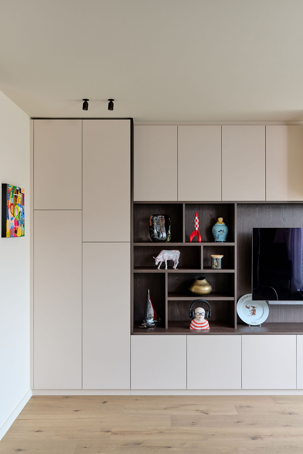 Mur TV sur mesure avec rangements fermés en tons clairs et niches ouvertes en finition bois, combinant esthétique et fonctionnalité dans un salon, réalisé par Camber