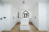 Witte dressing op maat met een centraal eiland en zwarte handgrepen, onder een puntdak met groot raam.