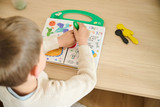 Enfant jouant avec un livre sur un meuble en bois clair dans un salon lumineux