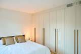 Chambre avec armoire sur mesure beige et lit double avec coussins assortis et lampe d’appoint