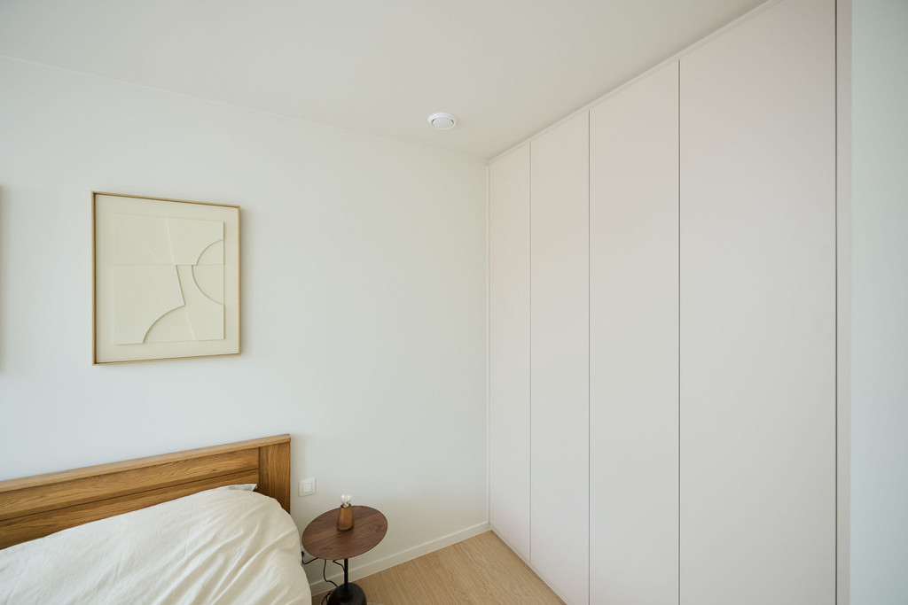 Armoire de chambre sur mesure avec portes sans poignées à côté d’un lit en bois