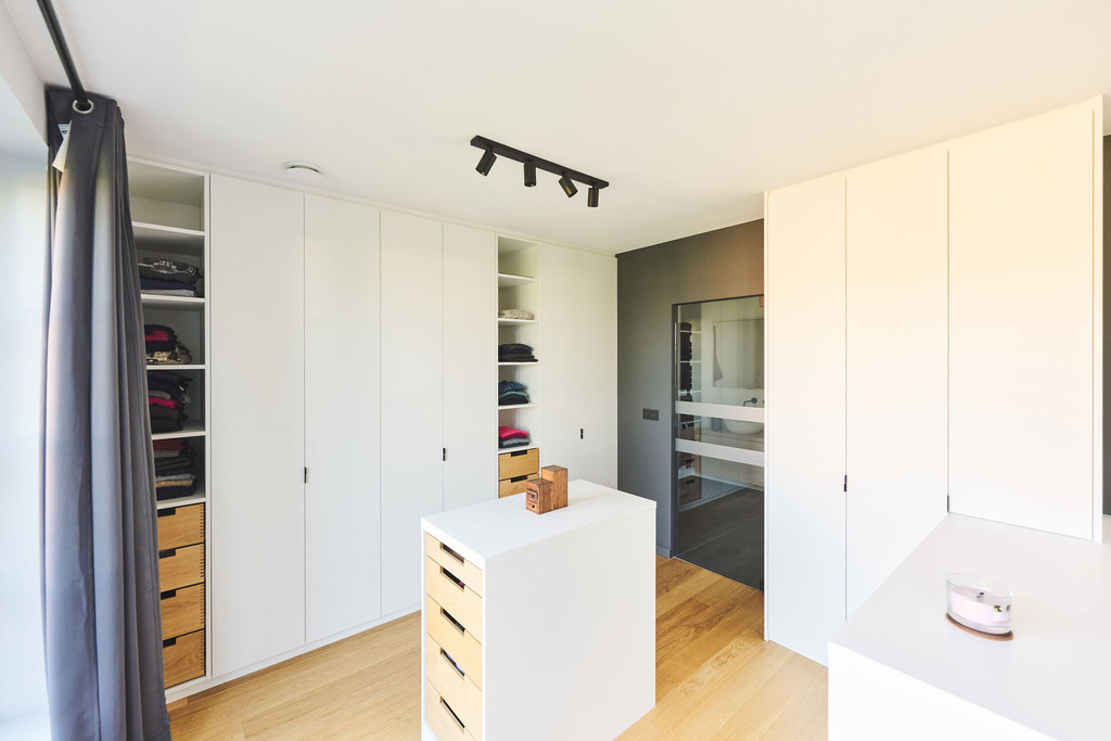 Dressing sur mesure avec îlot central, tiroirs en bois massif, armoires blanches et poignées intégrées