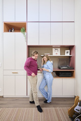 Couple devant une armoire blanche sur mesure avec coin musique panneau à lattes et amplificateur intégré