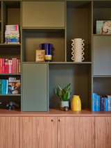 Open wandkast met boeken, accessoires en gele vaas op het dressoir